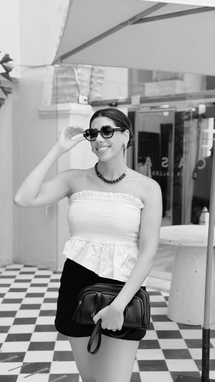 Antonia con lentes de sol bajo un quitasol, en blanco y negro