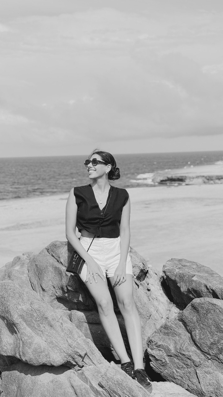 Antonia sentada en rocas frente al mar, en blanco y negro